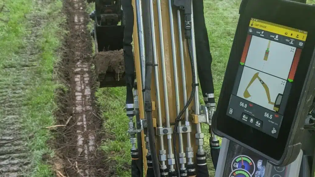 Trimble 2D grade control display inside excavator cab during lawn drainage project
